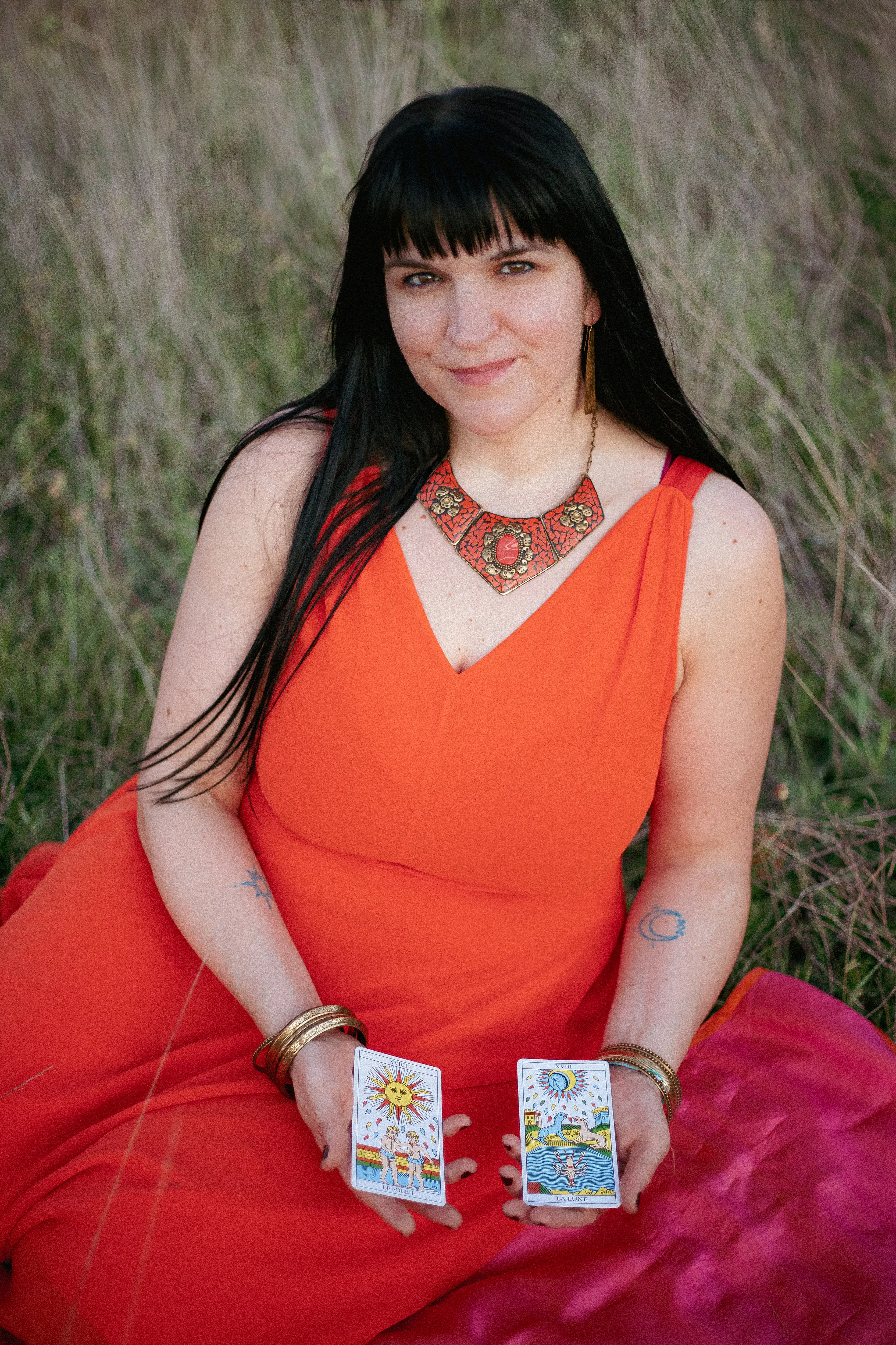 Adrienne Alberti holding the Sun and Moon tarot cards