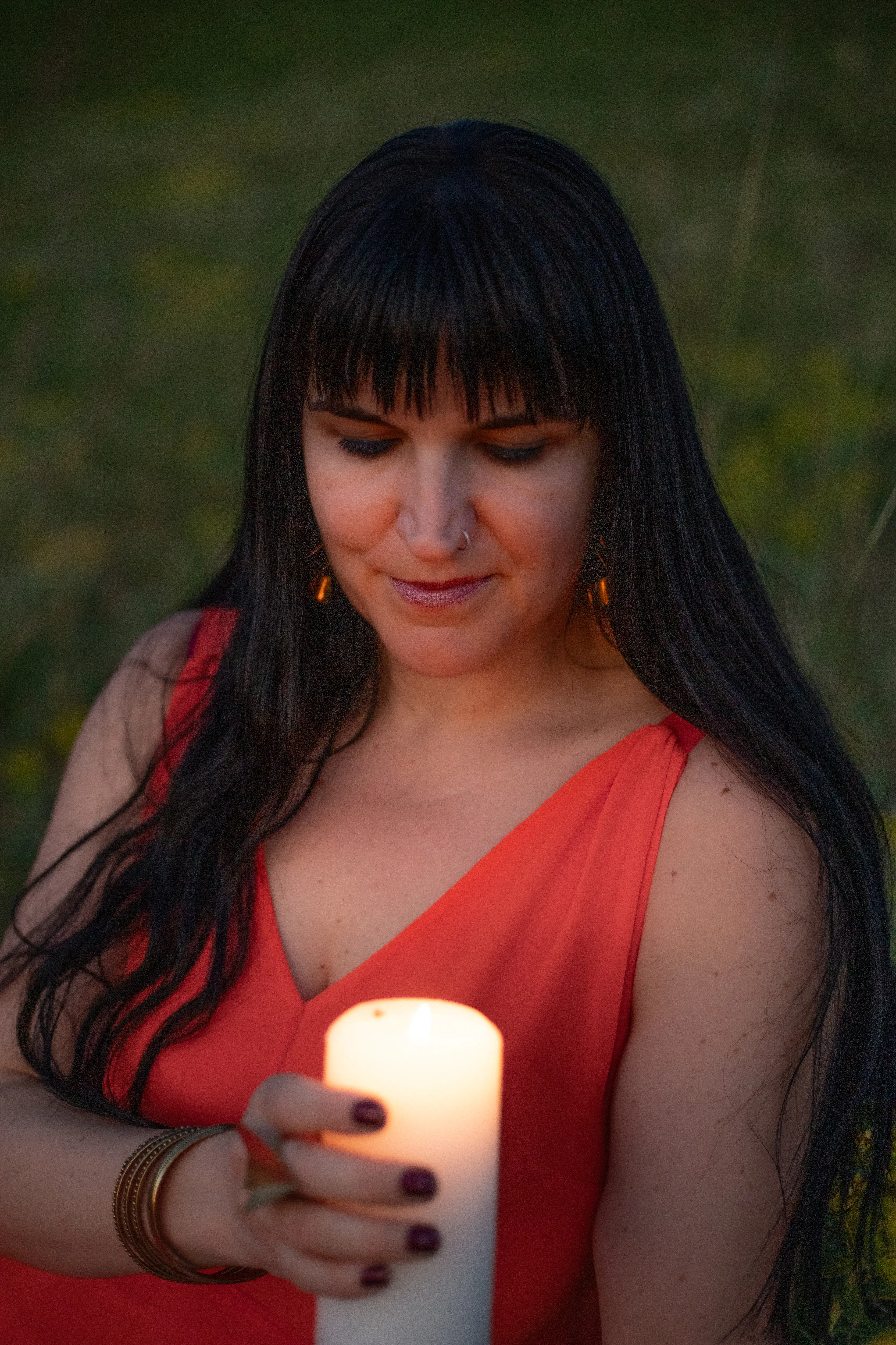 Close-up of Adrienne holding a lit candle at dusk