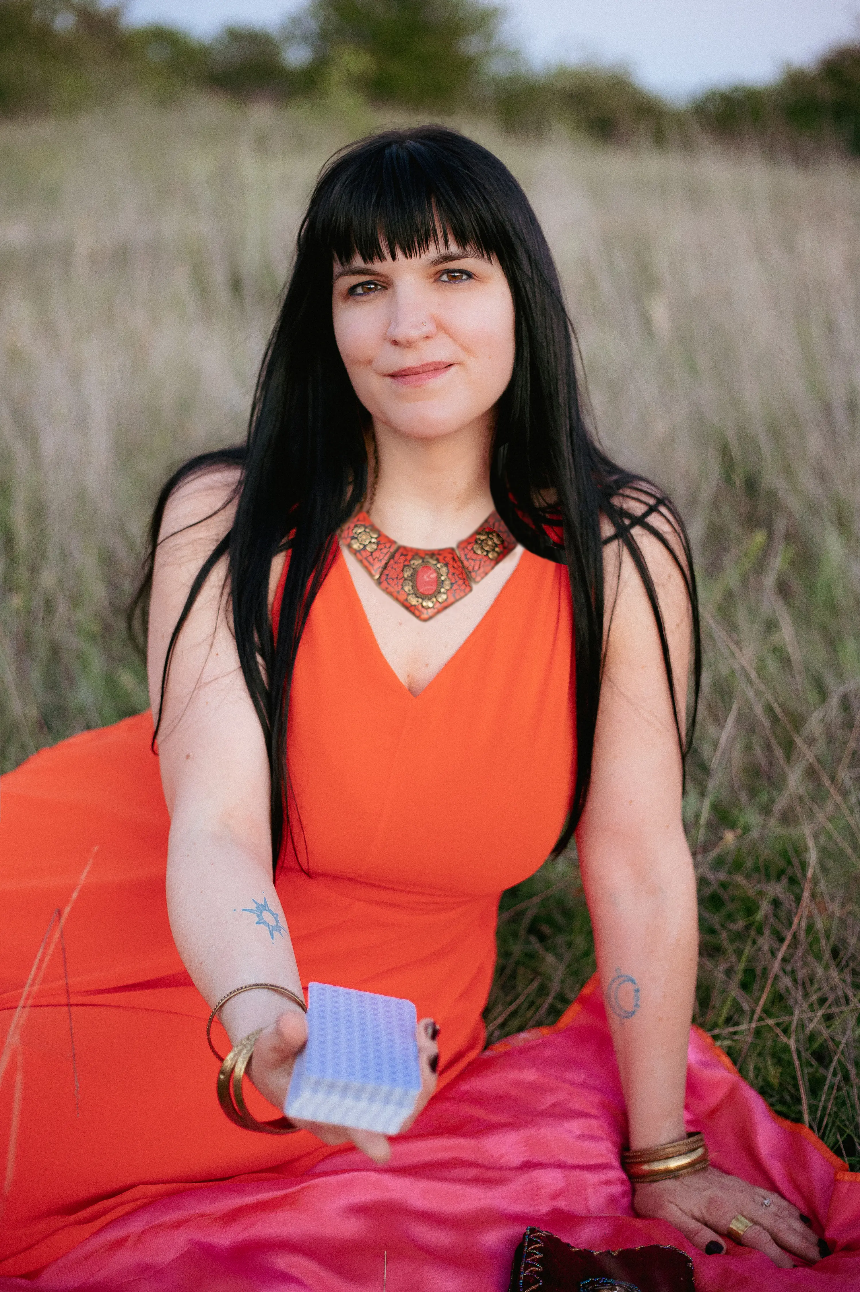 Adrienne Alberti sosteniendo las cartas de tarot El Sol y La Luna